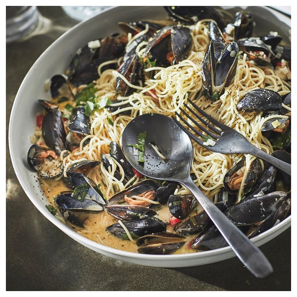 Plate of spaghetti with mussels, herbs, on rustic stoneware.