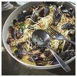 Plate of spaghetti with mussels, herbs, on rustic stoneware.