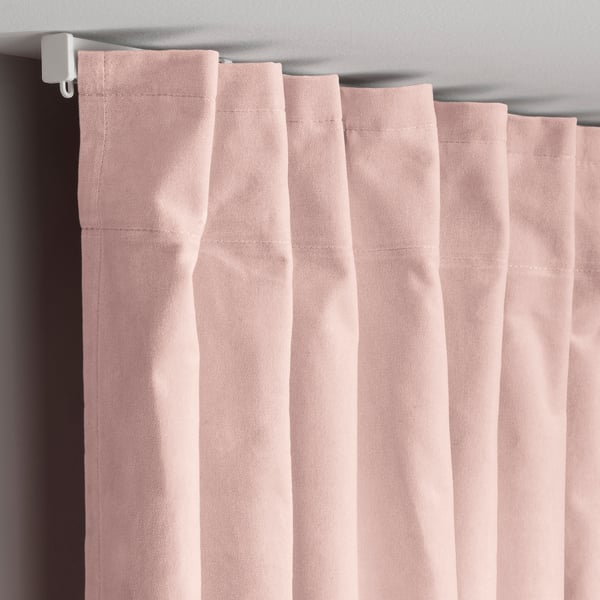 Light pink curtains hang neatly, showing pleated velvet texture. Rogue hooks secure top edges for elegant folds.