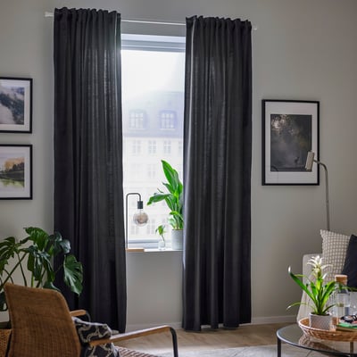 Dark grey velvet curtains frame large window, letting natural light.
