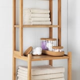 Bamboo shelf with neatly folded towels and organized jars, providing storage and easy access to bathroom essentials.