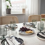 Table set with SILVERSIDA glassware and plates. Plates hold grapes and crackers. Wicker chairs surround the table.