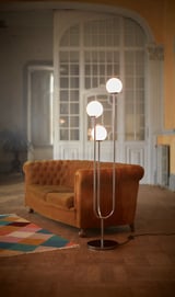 Modern living room with large arched window, orange curved sofa, colorful rug, and SIMRISHAMN chrome floor lamp with glass globes.
