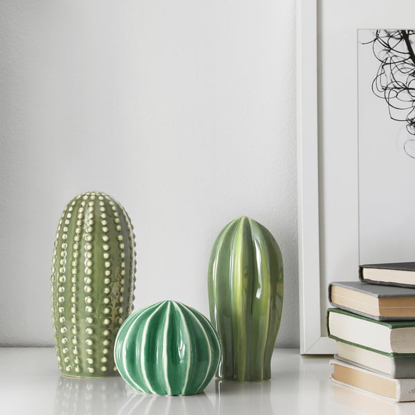 Three ceramic cacti on a shelf, resembling real plants, adding decorative greenery to home.