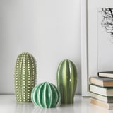 Three ceramic cacti on a shelf, resembling real plants, adding decorative greenery to home.