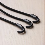 Black elastic cords with sturdy hooks on light-colored wooden surface.