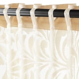 Sheer curtains with floral patterns on rod, allowing light while ensuring privacy.