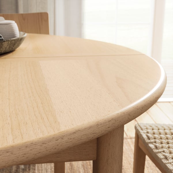 A round, light wood dining table with a smooth, natural finish, extending to seat 6, showcasing scandinavian design.