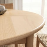 A round, light wood dining table with a smooth, natural finish, extending to seat 6, showcasing scandinavian design.