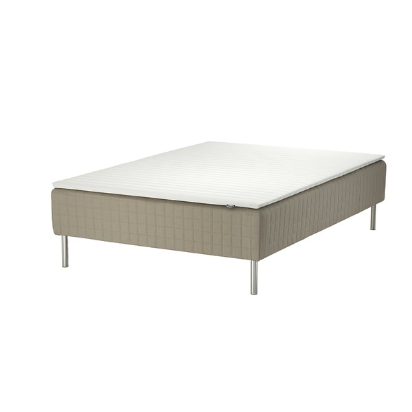 A skärer bed with a white mattress on a beige base supported by metal legs.