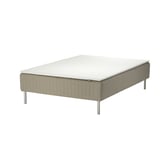A skärer bed with a white mattress on a beige base supported by metal legs.