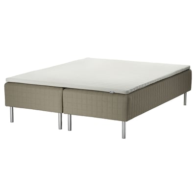 An IKEA skärer bed with a beige, quilted fabric base, a white mattress, and four silver legs.