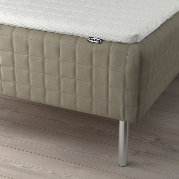 Bed base with attached sprung mattress and legs. IKEA brand label and soft, padded design.