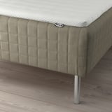 Bed base with attached sprung mattress and legs. IKEA brand label and soft, padded design.