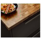 Wooden kitchen counter with bowl, chopsticks, and food, featuring natural oak finish and end-grain design.