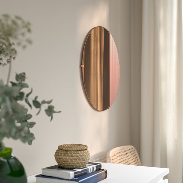 A wall-mounted mirror with rose-gold tones and soft lighting adds warmth to any room.