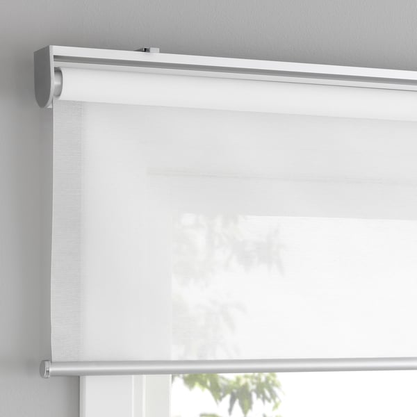 White roller blind with soft closing, cordless for safety, mounted inside window recess, diffuses light during day.