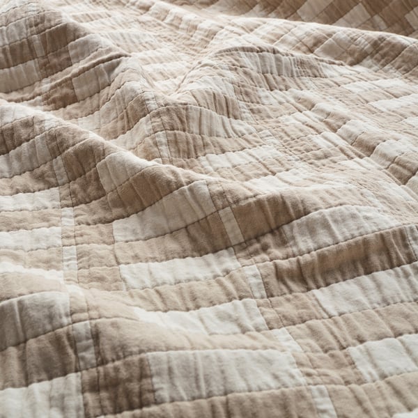 Close-up of a textured, cream-colored fabric with visible stitching, showcasing its quality and density.