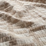 Close-up of a textured, cream-colored fabric with visible stitching, showcasing its quality and density.