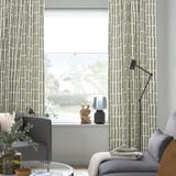 Modern room with SKOGSSTJÄRNA curtains, green-gray patterns, and a cozy gray sofa with a basket.