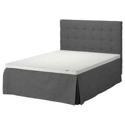 Dark grey upholstered bed with foam mattress.