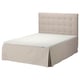 A beige upholstered bed with a tufted headboard and a skirted base.