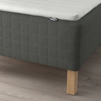A modern bed with a dark green SKOTTERUD mattress and wooden legs. The white mattress label shows the ikea logo.