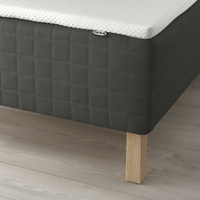 Image a mattress with wooden legs and a padded bottom, likely highlighting the mattresss support and comfort.