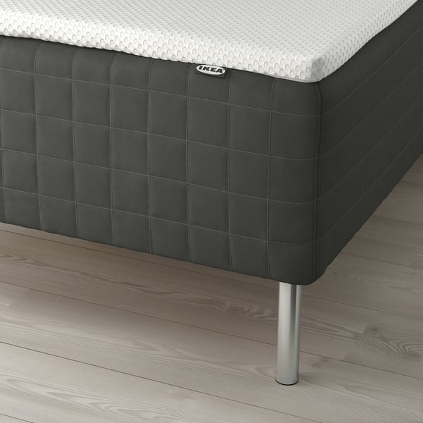 Close-up of ikea SKOTTERUD mattress on wooden floor with legs, showing pocket springs and memory foam.