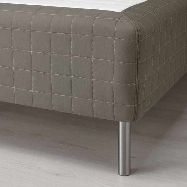 Close-up of a sprung mattress with wooden base leg, showcasing fine stitching and supportive design.