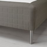 Close-up of a sprung mattress with wooden base leg, showcasing fine stitching and supportive design.