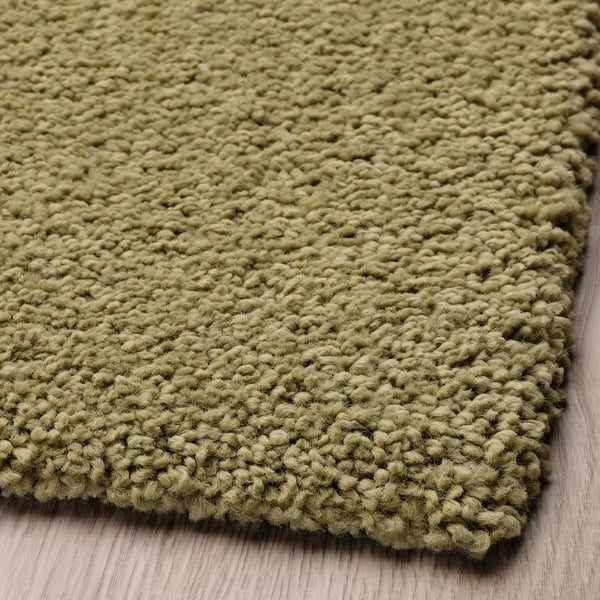 Soft, textured olive-green area rug, close-up view showcasing thick, cozy fibers.