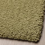 Soft, textured olive-green area rug, close-up view showcasing thick, cozy fibers.