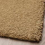 Soft beige rug with dense, woven texture, displayed on wooden floor.