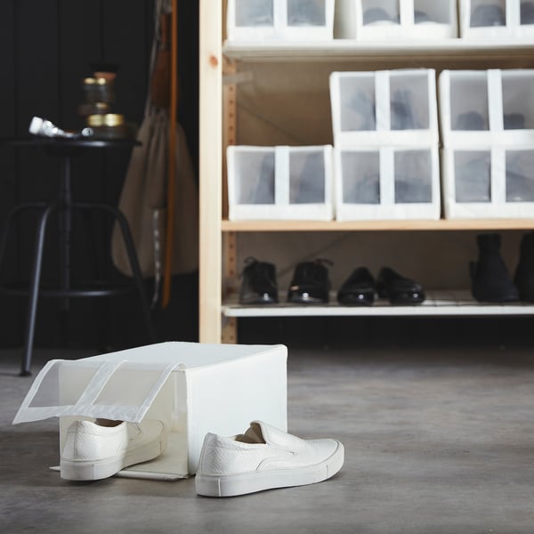 White sneakers in mesh box on shelf.