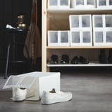 White sneakers in mesh box on shelf.