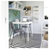 Modern office with SKURUP lamp, sleek desk, gray chair, and striped rug.