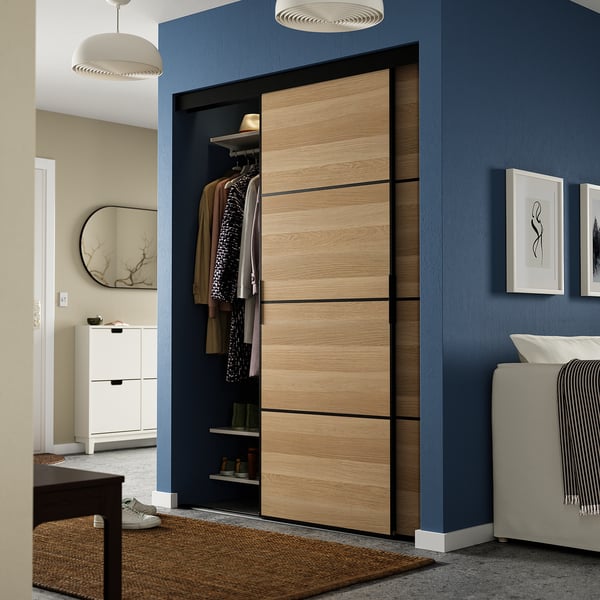 Modern grey bedroom with grey closet, partially open, between mirror & bed.