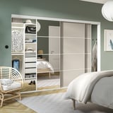 Modern bedroom with light wardrobe & mirrored doors. Central bed, wicker chair, & soothing colors.
