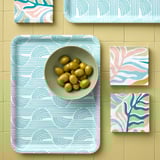 A decorative tray holds a bowl of olives on a colorful backsplash with patterned tiles.
