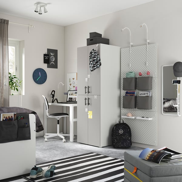 Teen bedroom with gray SMÅSTAD wardrobe, black backpack, striped rug, and desk with chair.