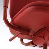 Red office chair close-up; curved armrest, adjustable tilt, smooth castors.