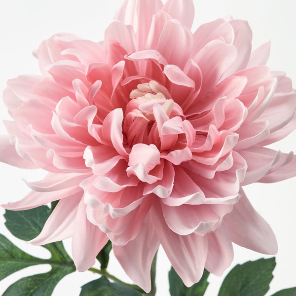 Close-up of lifelike artificial pink flower with delicate petals and green leaves, made from recycled materials.