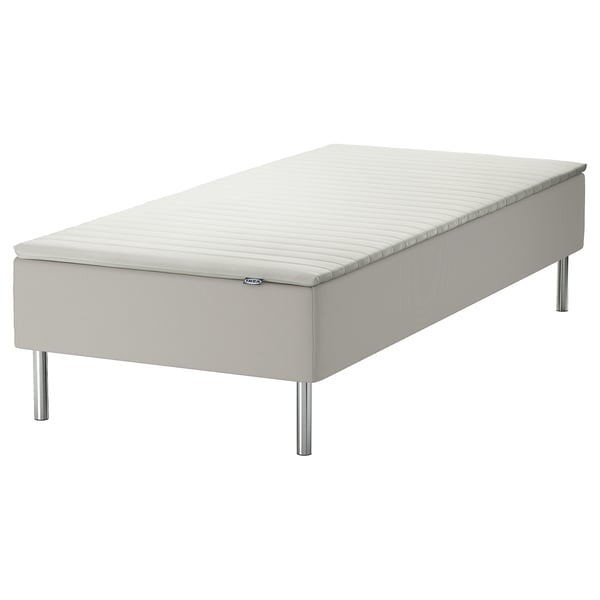 A white IKEA SNARUM bed. It a padded base with stainless steel legs and a zippered mattress topper.