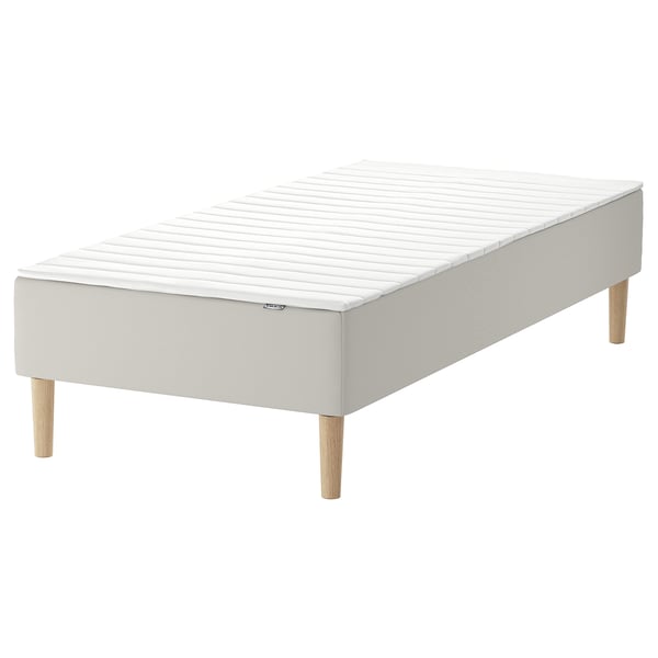 White SNARUM bed base with sprung mattress, wooden legs.