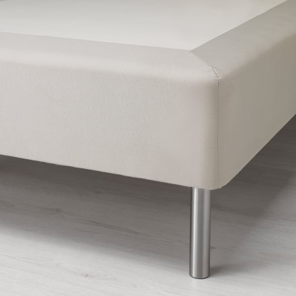Image shows a corner of a modern, upholstered bed frame on metal legs, highlighting its sleek and sturdy design.