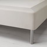 Image shows a corner of a modern, upholstered bed frame on metal legs, highlighting its sleek and sturdy design.