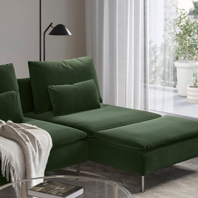Dark green modern sectional sofa with chaise, pillows, and mini lamp situated next to a large window.
