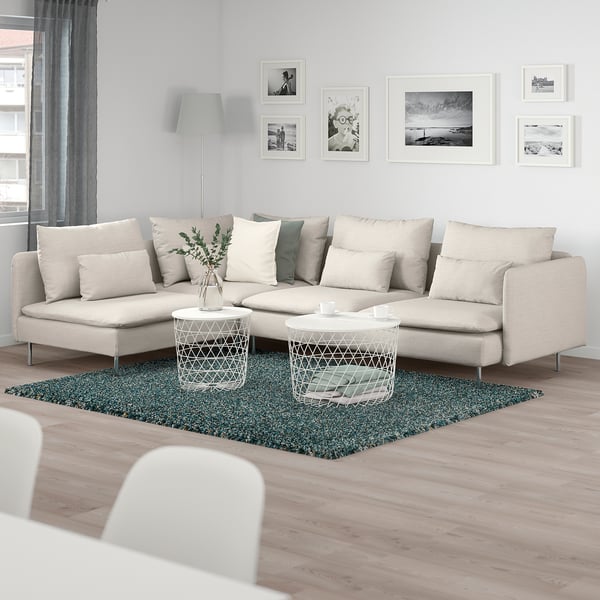 Modern living room with SÖDERHAMN sofa, green rug, two coffee tables, art, and lamp.