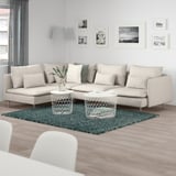 Modern living room with SÖDERHAMN sofa, green rug, two coffee tables, art, and lamp.
